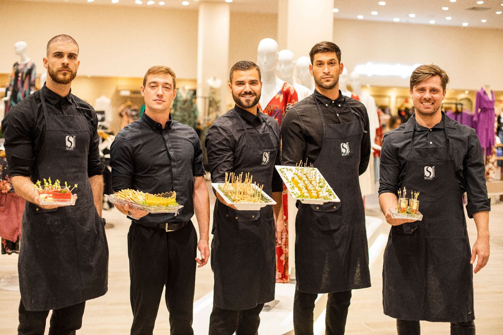 Equipe profissional Staff Eventos uniformizada servindo aperitivos gourmet em evento corporativo